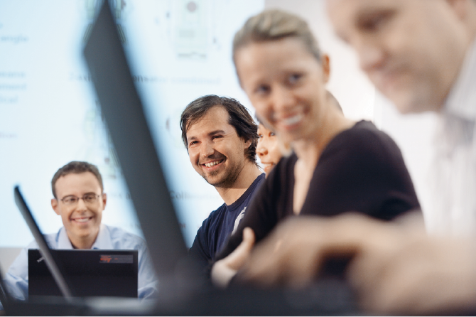 Equipe en réunion travaillant sur leurs ordinateurs en souriant